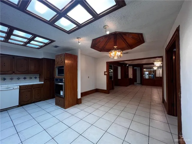 a view of an empty room with kitchen and a window