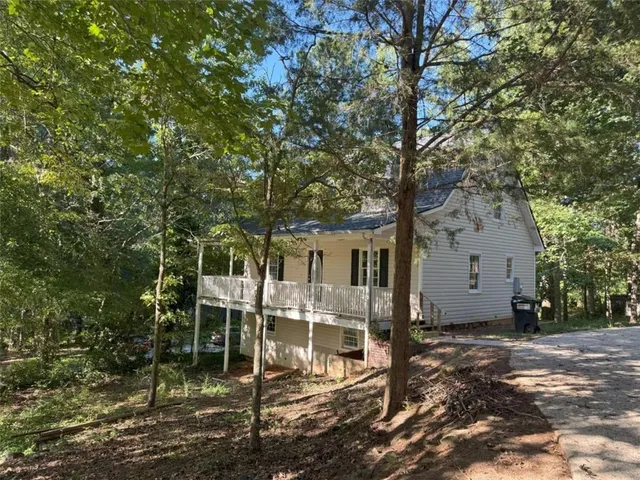 a view of a big house with large trees and plants