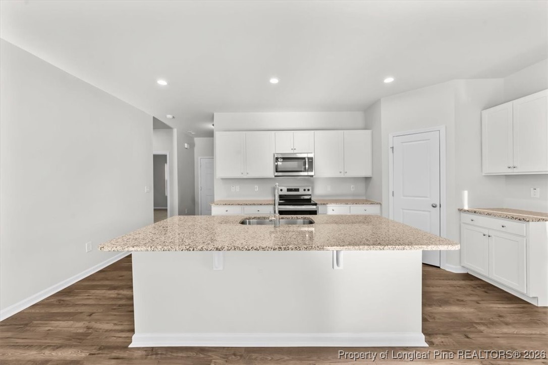 266 Happy Trail Road Aberdeen, NC 28315 - Photo 14 of 34 a large kitchen with kitchen island a stove a sink a refrigerator and white cabinets
