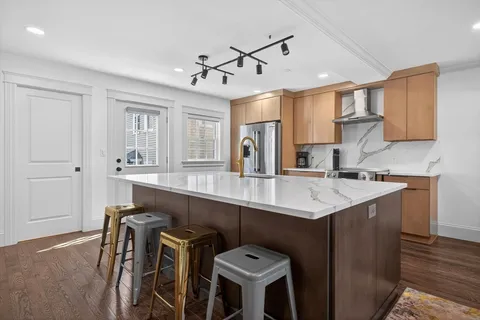 a kitchen with stainless steel appliances kitchen island granite countertop a stove and a wooden floors