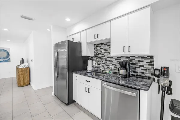 a kitchen with granite countertop a sink a stove and cabinets