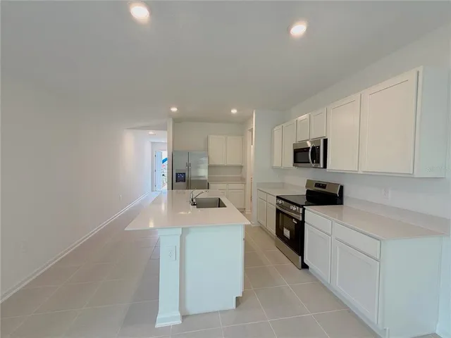 a large white kitchen with stainless steel appliances granite countertop a sink dishwasher a stove and white cabinets with wooden floor