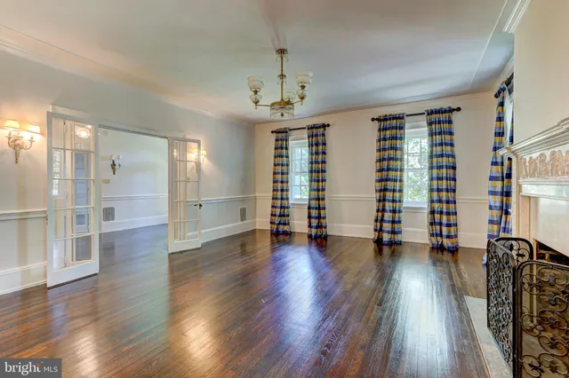 a view of an empty room with wooden floor and windows