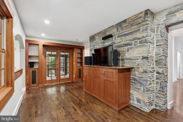 an empty room with wooden floor chandelier and windows