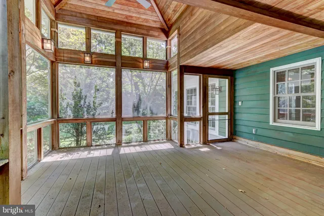a view of an empty room with wooden floor fireplace and a window
