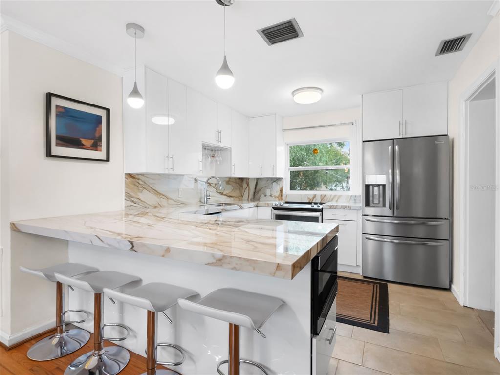 1632 Pinewood Drive Orlando, FL 32804 - Photo 12 of 28 a kitchen with stainless steel appliances granite countertop a refrigerator a sink a stove a dining table and chairs