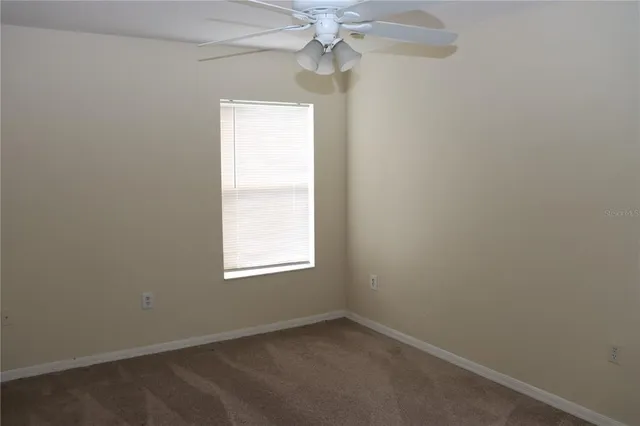 an empty room with a window and a fan