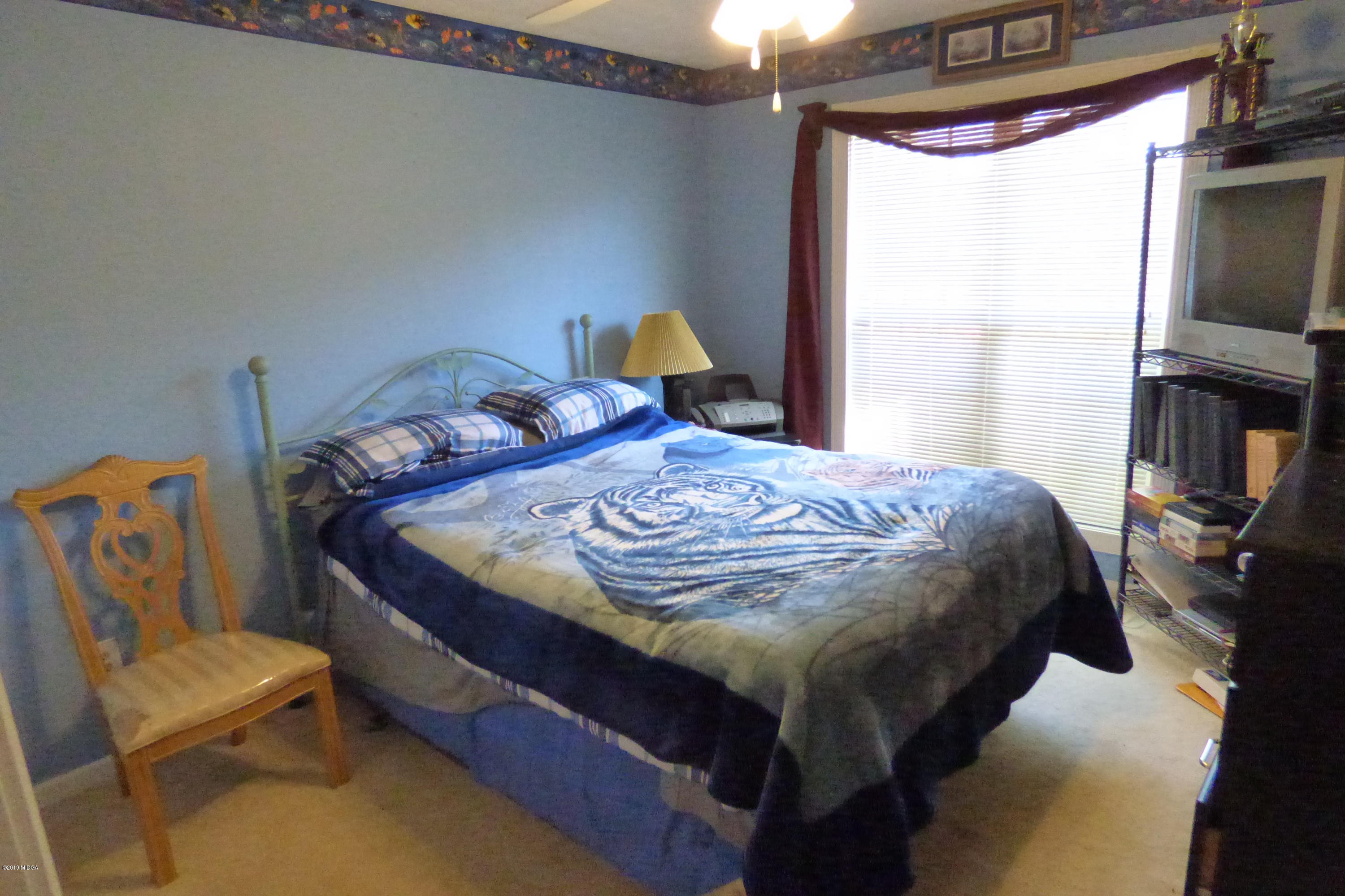 323 Rustin Road Reynolds, GA 31076 - Photo 12 of 25 a bedroom with a bed and a flat tv screen on the dresser