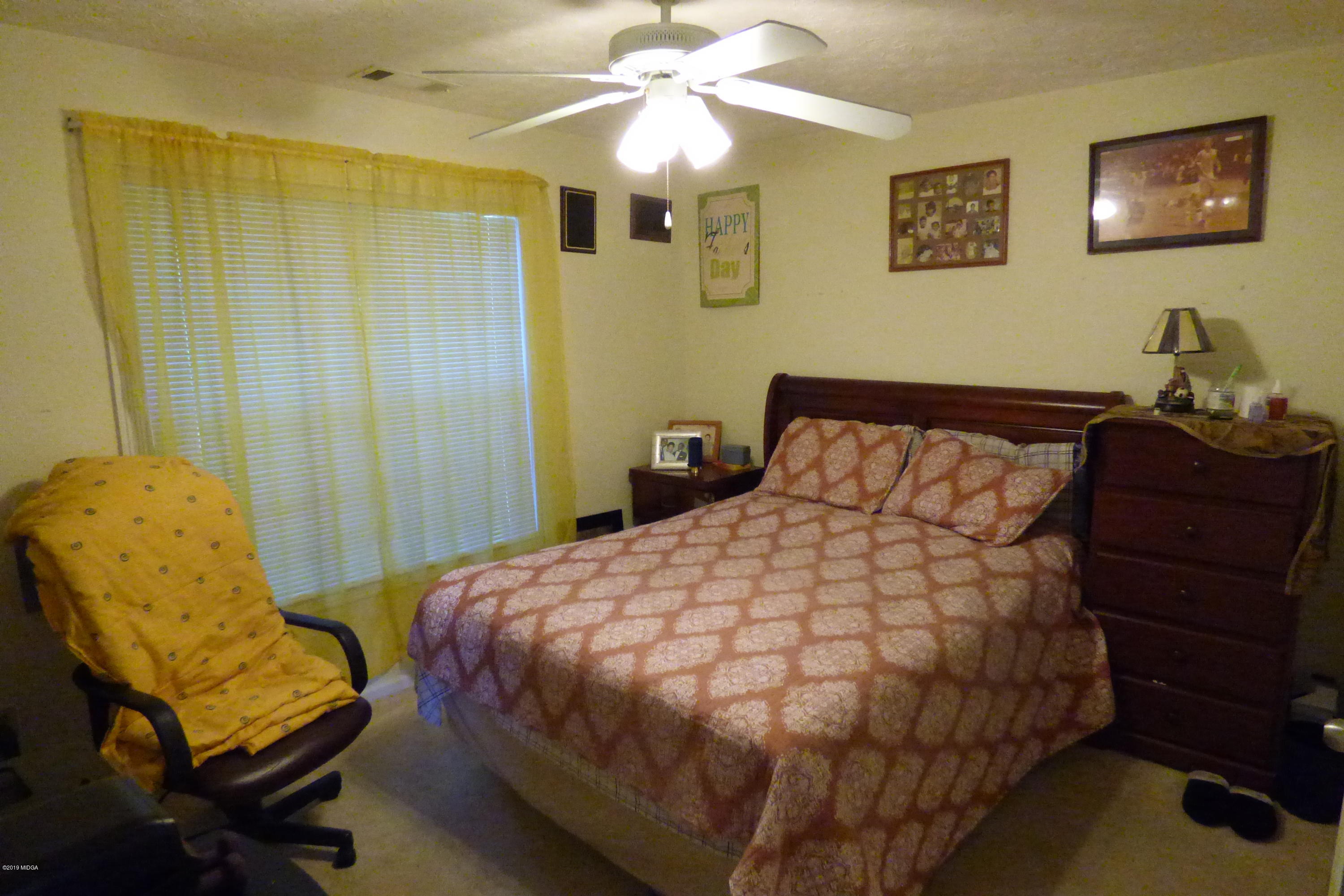 323 Rustin Road Reynolds, GA 31076 - Photo 13 of 25 a bedroom with a bed and a chandelier