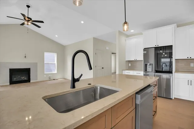 a view of a kitchen with kitchen island stainless steel appliances wooden floor cabinets and a window