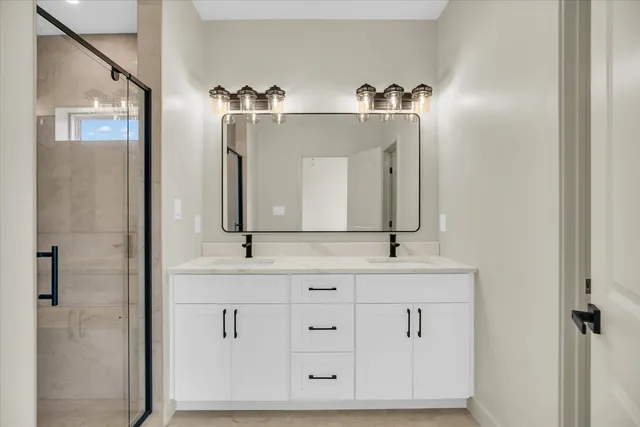 a bathroom with a double vanity sink mirror and shower