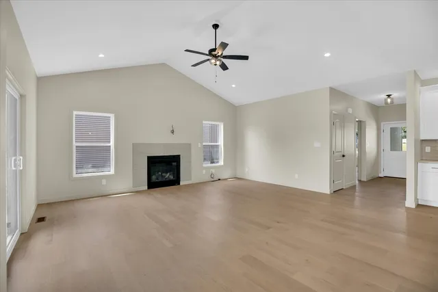 a view of an empty room with a window and wooden floor