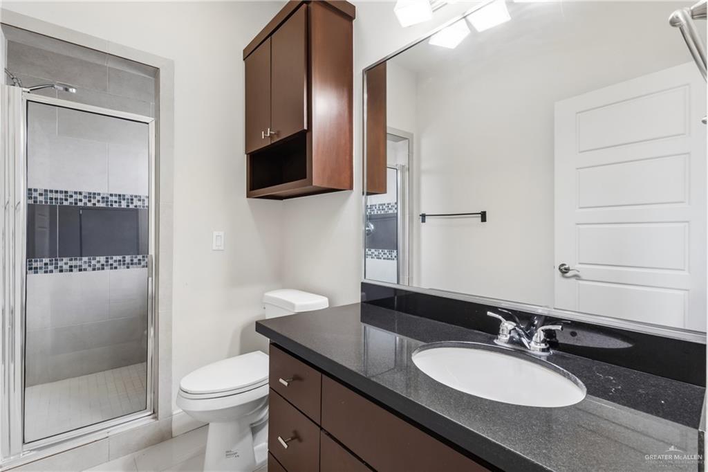 3016 South L Street, Unit 2 McAllen, TX 78503 - Photo 9 of 16 a bathroom with a granite countertop sink toilet a mirror and shower