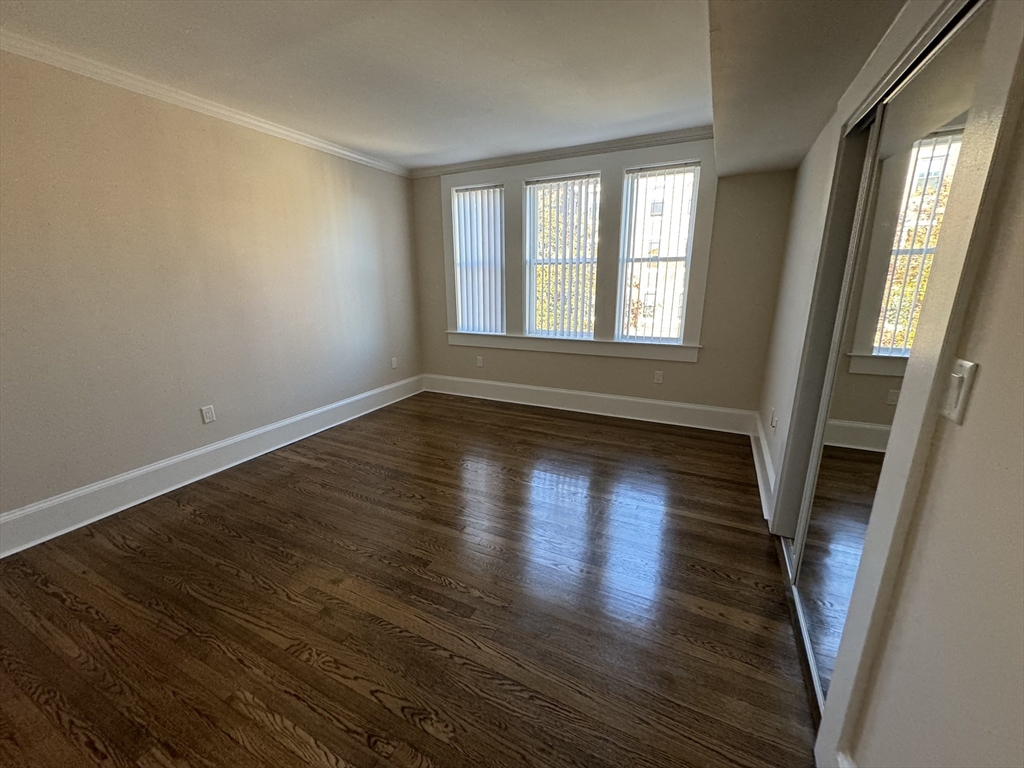 18 Short Street, Unit 3 Brookline, MA 02446 - Photo 4 of 14 a view of an empty room with wooden floor and a window