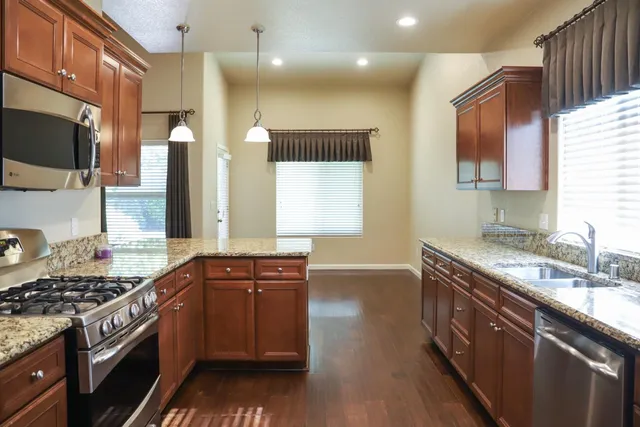 a kitchen with stainless steel appliances granite countertop a stove a sink and a microwave