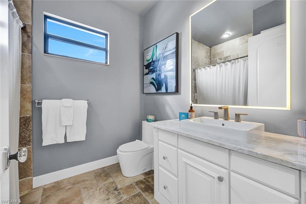 494 Seagull Avenue Naples, FL 34108 - Photo 14 of 32 a bathroom with a granite countertop sink mirror vanity and toilet