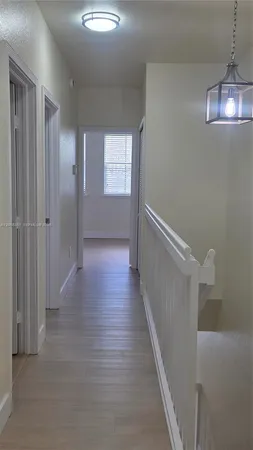 a view of a hallway with wooden floor and chandelier