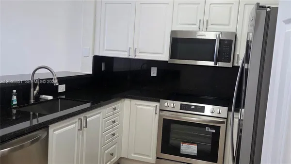 a kitchen with granite countertop white cabinets and stainless steel appliances