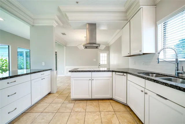 a kitchen with granite countertop a sink stainless steel appliances white cabinets and a window