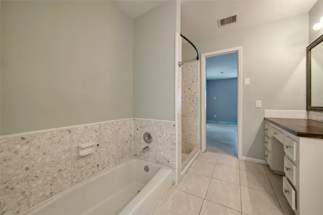 a spacious bathroom with a granite countertop sink and a bathtub