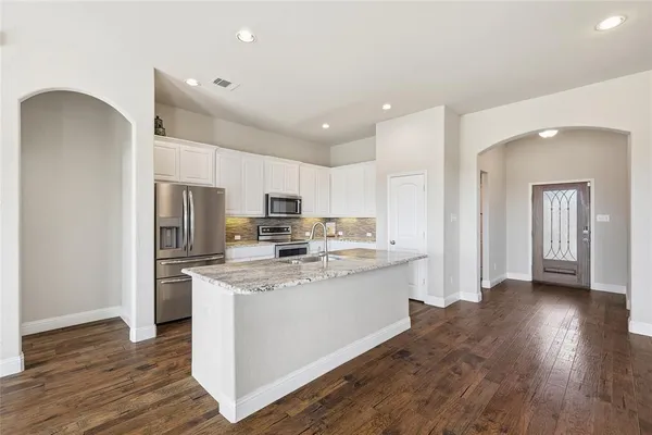 a view of kitchen with cabinets stainless steel appliances and wooden floor