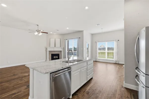 a kitchen with stainless steel appliances granite countertop a stove top oven a sink and a granite counter tops with white walls