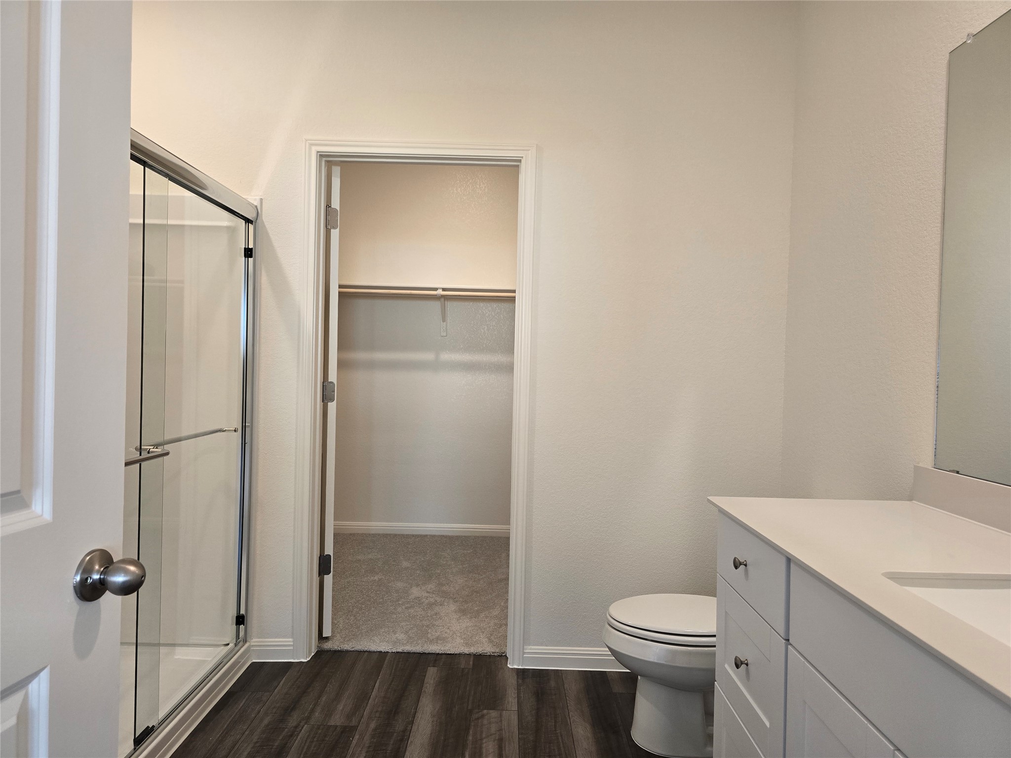 509 McFadin Way Taylor, TX 76574 - Photo 16 of 23 Full bath featuring a walk in closet, dark wood finished floors, a shower stall, and vanity