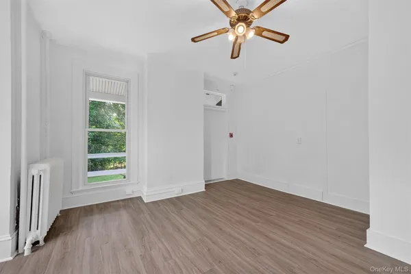 an empty room with wooden floor fan and windows