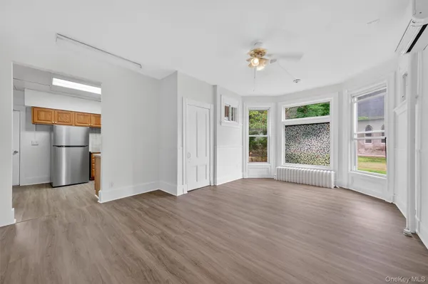 an empty room with wooden floor chandelier and windows