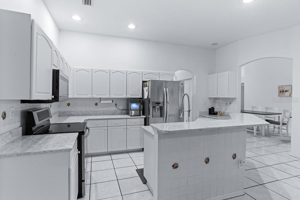 828 Innergary Place Valrico, FL 33594 - Photo 5 of 20 a kitchen with white cabinets a sink stove and refrigerator