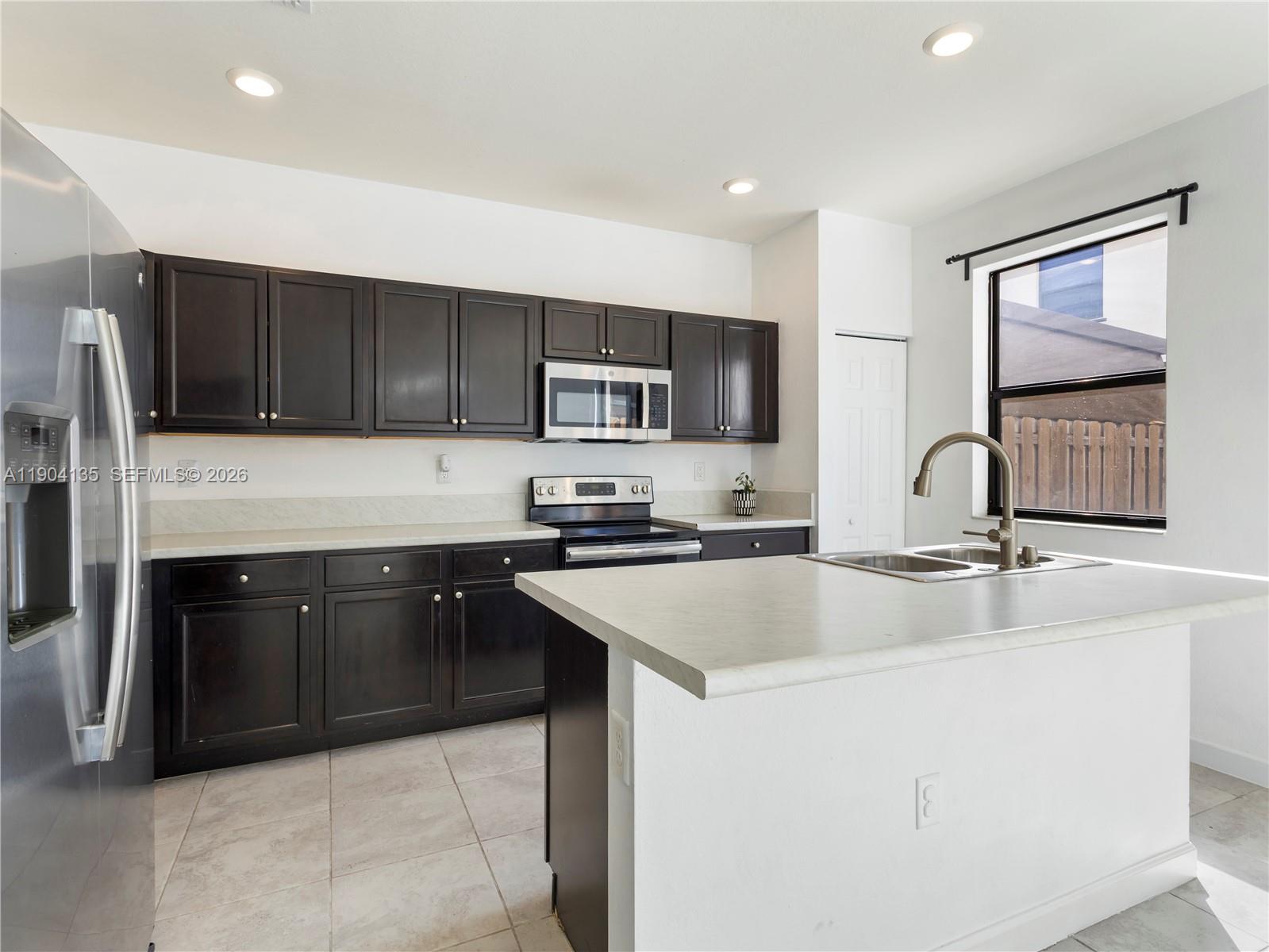 11410 Southwest 252nd Terrace Homestead, FL 33032 - Photo 14 of 38 a kitchen with stainless steel appliances granite countertop a sink stove and refrigerator