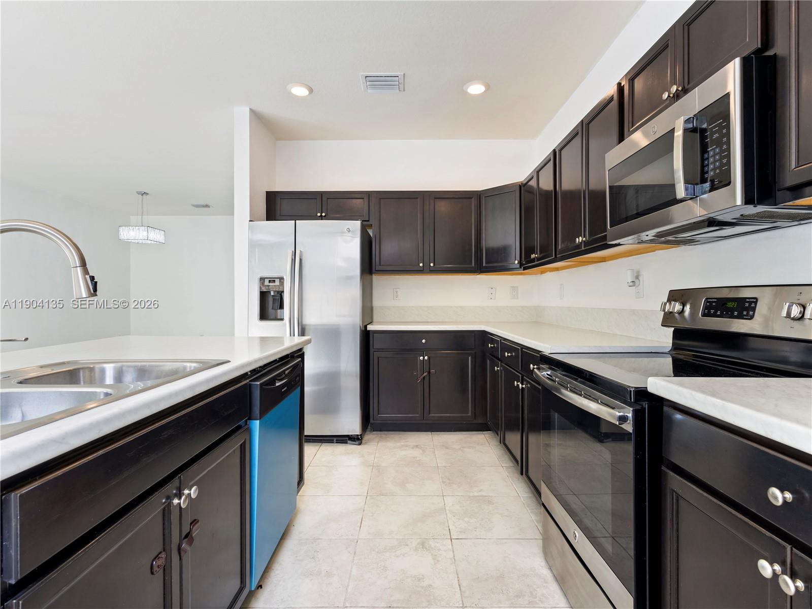 11410 Southwest 252nd Terrace Homestead, FL 33032 - Photo 17 of 38 a kitchen with stainless steel appliances granite countertop a sink stove and refrigerator