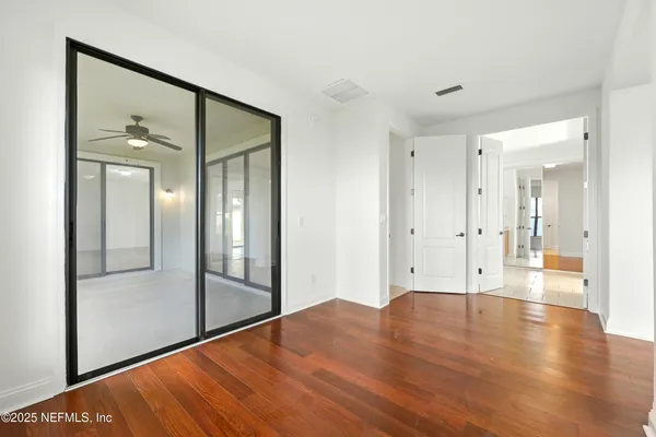 an empty room with wooden floor and windows