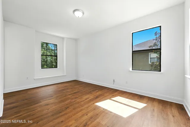 a backyard of a house with plants and large tree