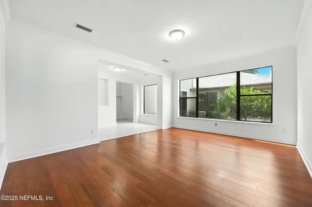 an empty room with wooden floor and windows