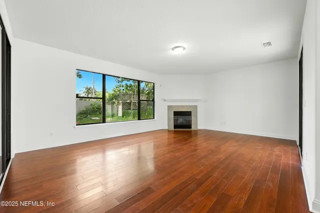 a view of an empty room with window and wooden floor
