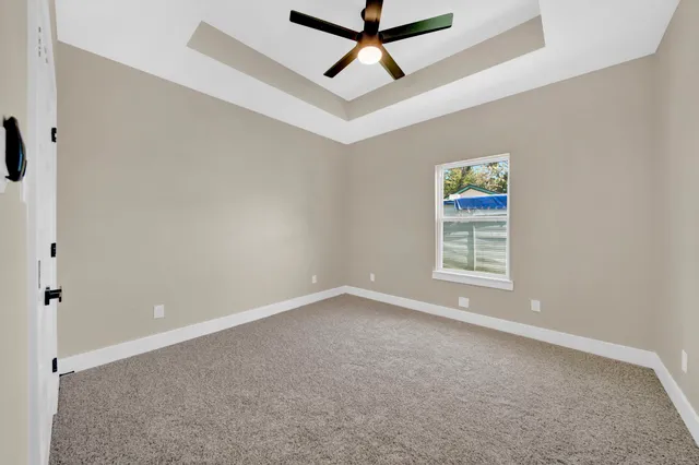 an empty room with windows and ceiling fan