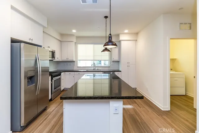 a kitchen with kitchen island a counter top space a sink stainless steel appliances and cabinets