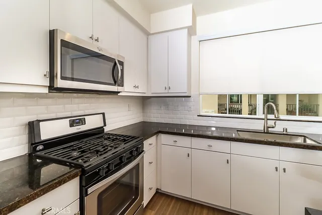 a kitchen with granite countertop a sink a stove and cabinets