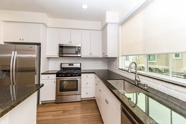 a kitchen with stainless steel appliances granite countertop a stove a sink and a microwave