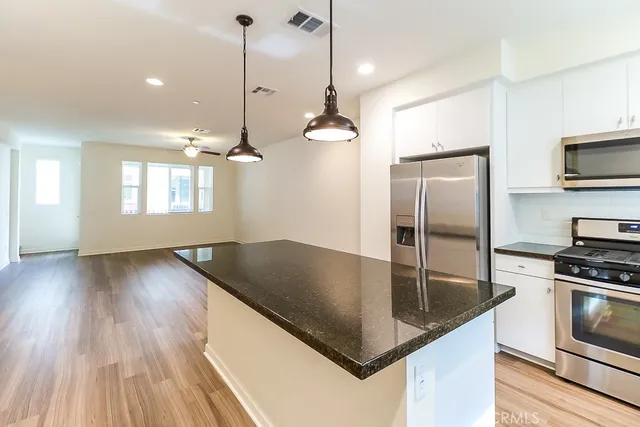 a kitchen with stainless steel appliances granite countertop a sink a refrigerator and wooden floor
