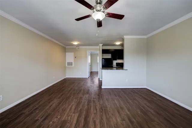 a view of a room with wooden floor a ceiling fan and a window