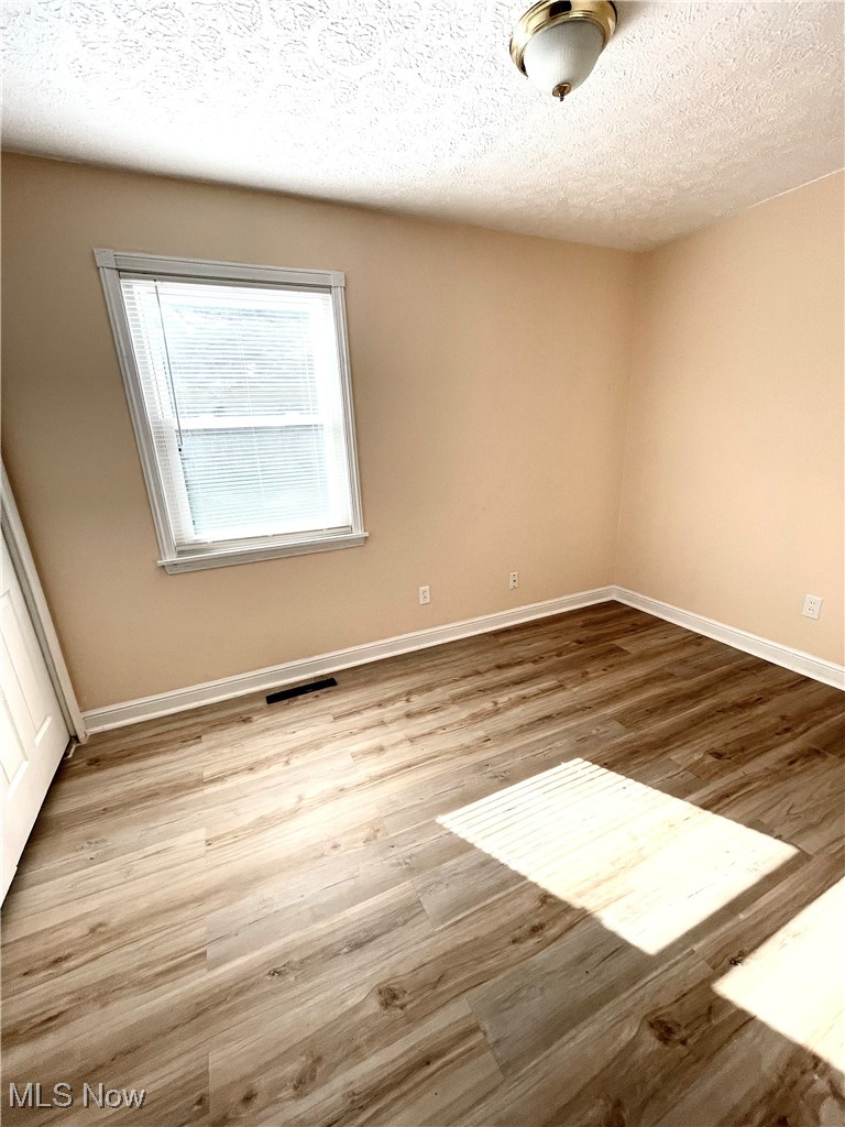 1816 Aberdeen Road Madison, OH 44057 - Photo 7 of 12 Spare room featuring light wood-type flooring and a textured ceiling
