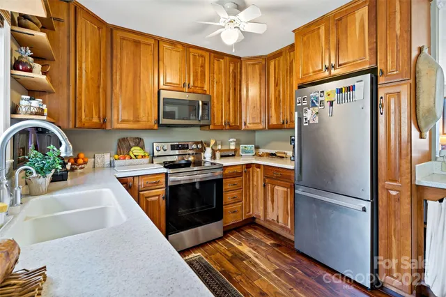 a kitchen with stainless steel appliances granite countertop a refrigerator a stove a sink and a microwave with wooden floor