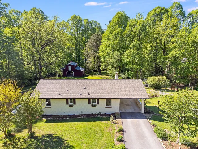 an aerial view of a house with swimming pool and large trees