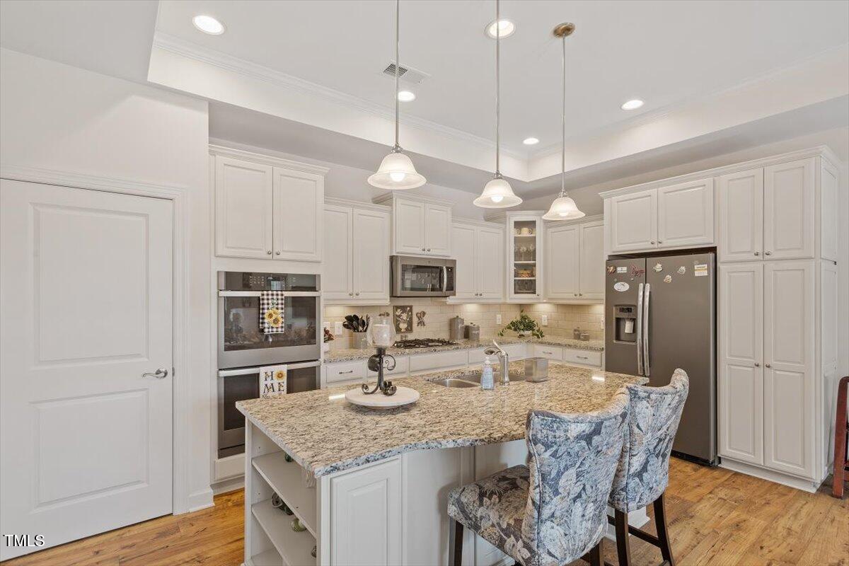 1357 Prevenient Drive Wake Forest, NC 27587 - Photo 19 of 58 a kitchen with kitchen island granite countertop a refrigerator a sink a center island and wooden floor