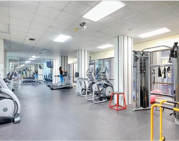 a view of a patio with couches table and chairs under an umbrella with large trees