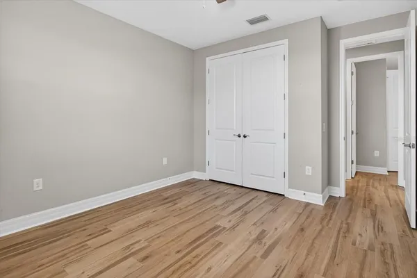 a view of an empty room with wooden floor and a ceiling fan