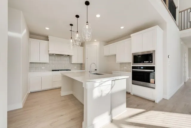 a large white kitchen with kitchen island a sink appliances and cabinets
