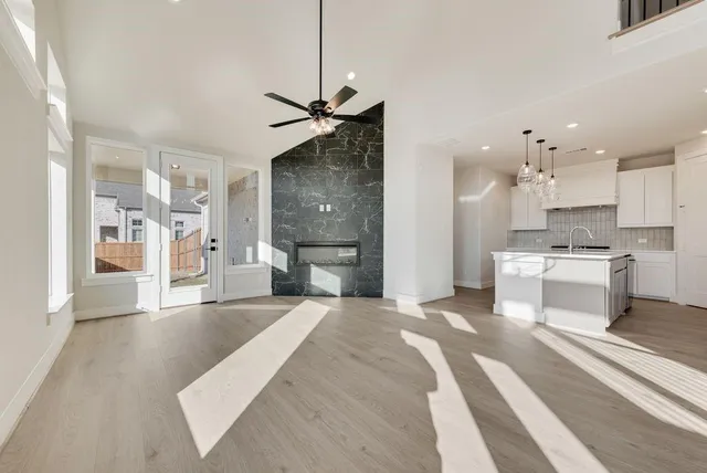 a large white kitchen with a refrigerator a stove a sink dishwasher and a dining table with wooden floor